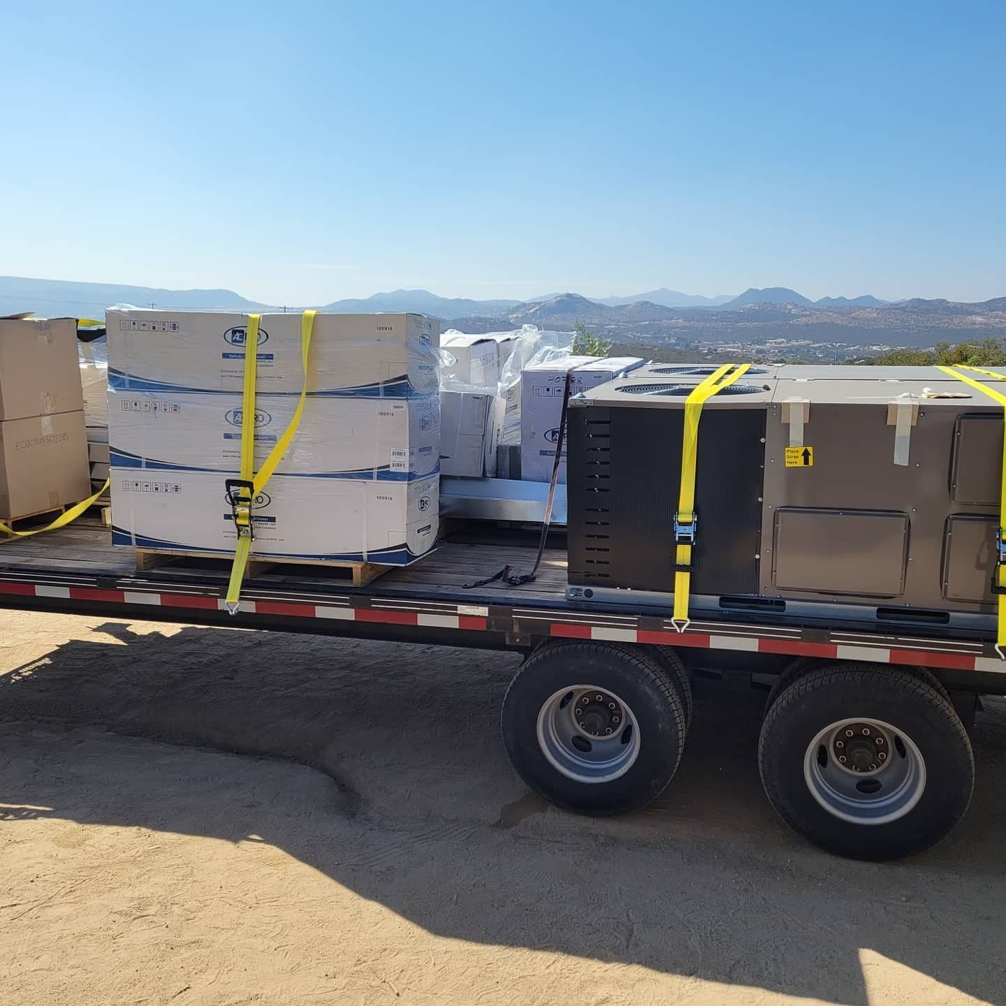 Flatbed with new HVAC equipment in front of mountains
