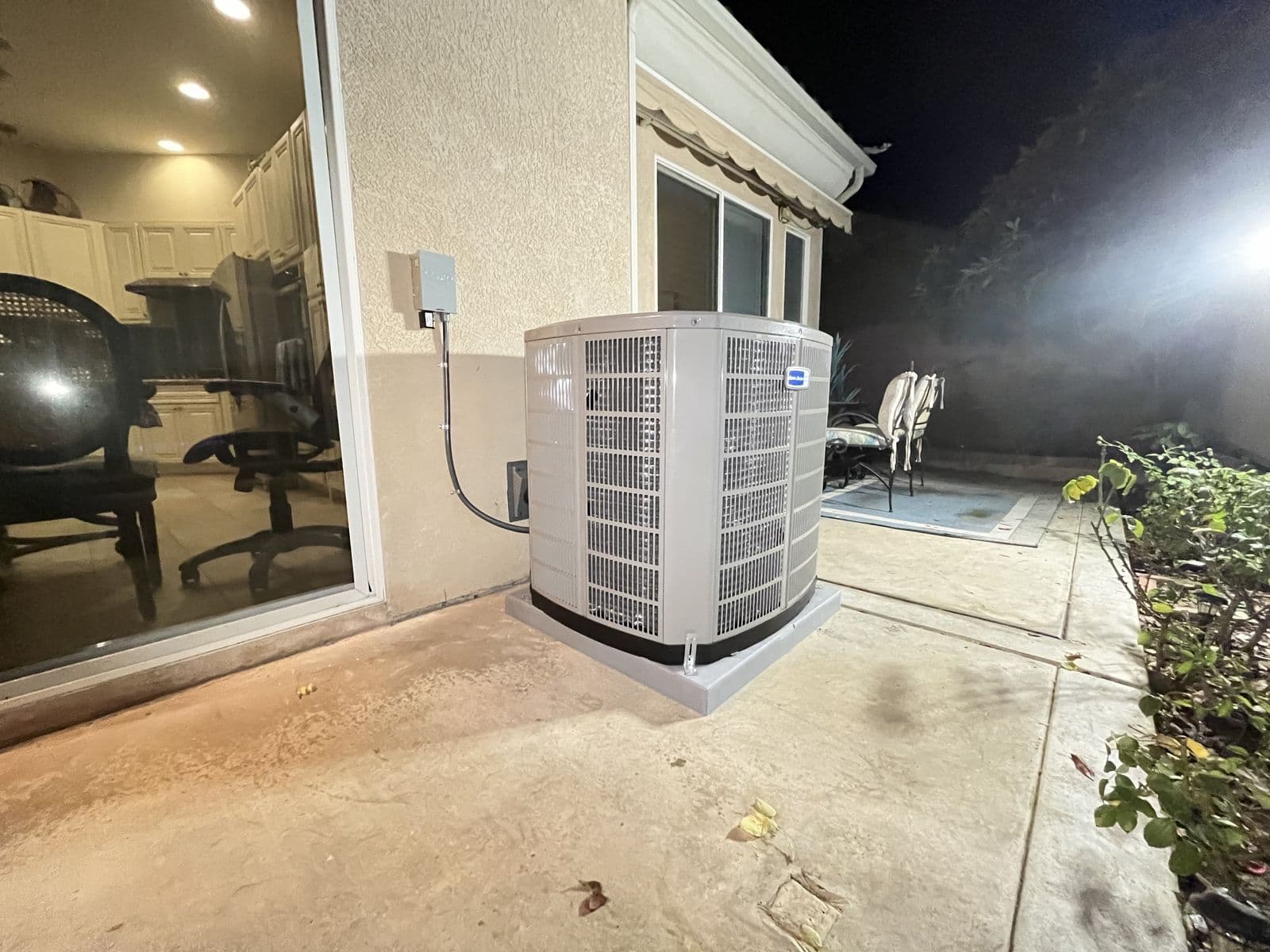 New outdoor unit installed beside a patio at night
