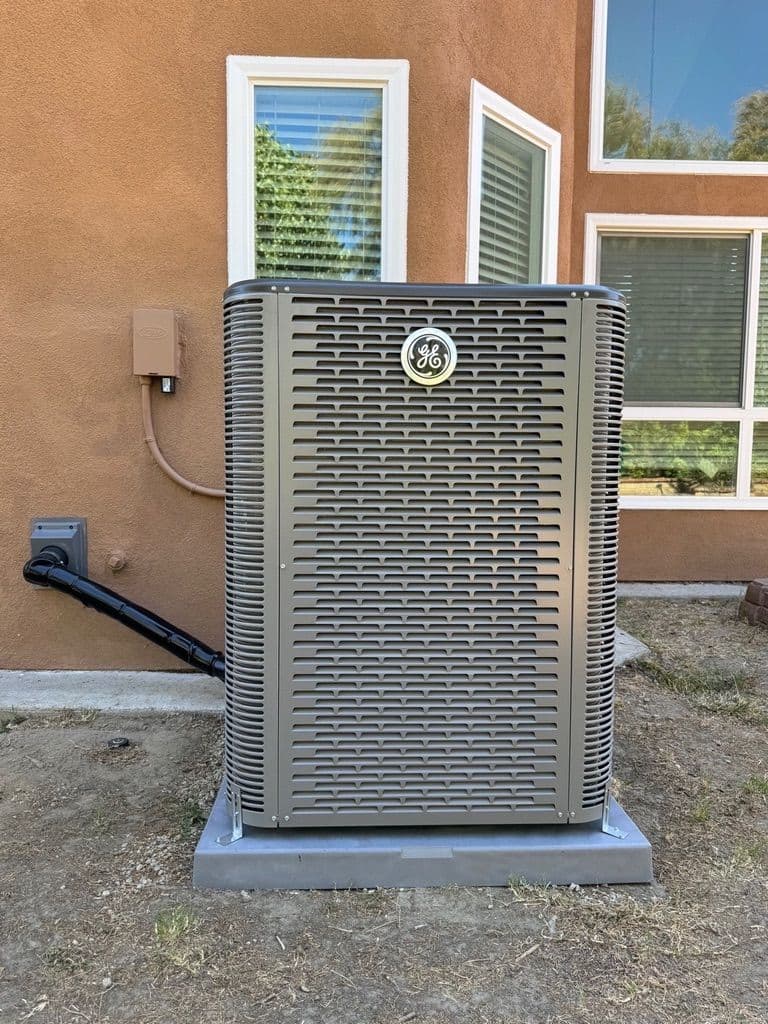 New tall condenser on a pad beside a stucco wall
