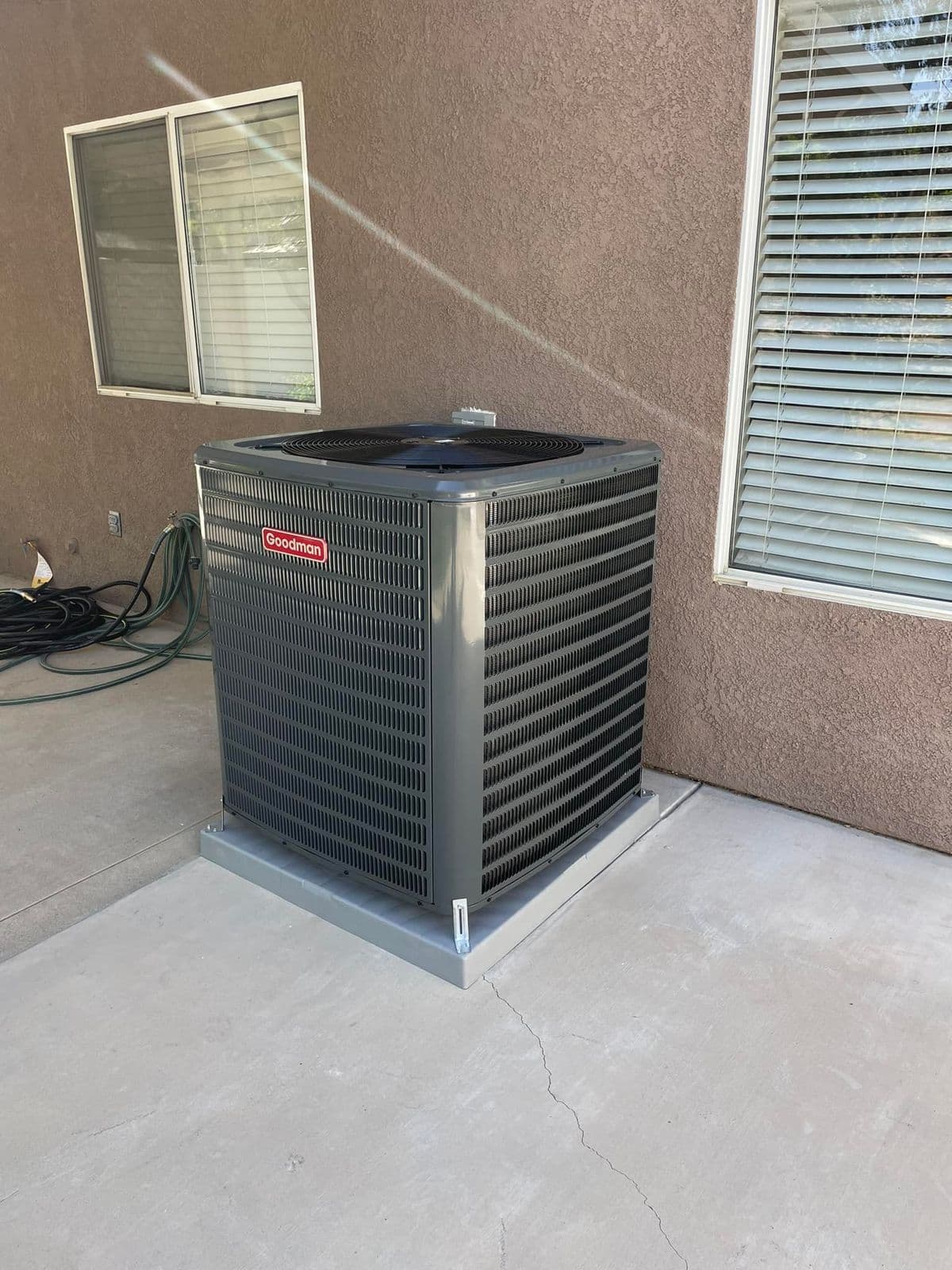 Newly installed outdoor unit beside a stucco wall and window