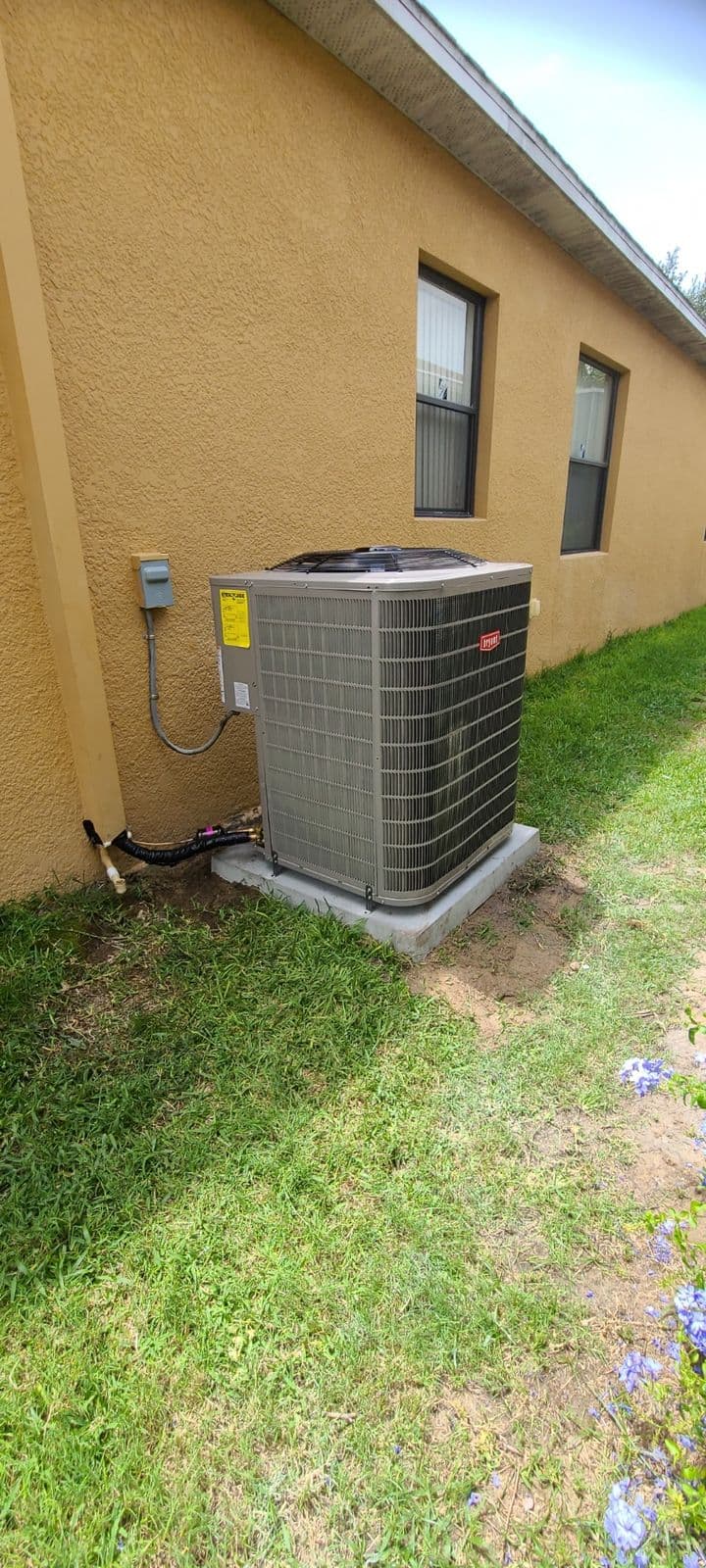 Condenser beside a yellow stucco house