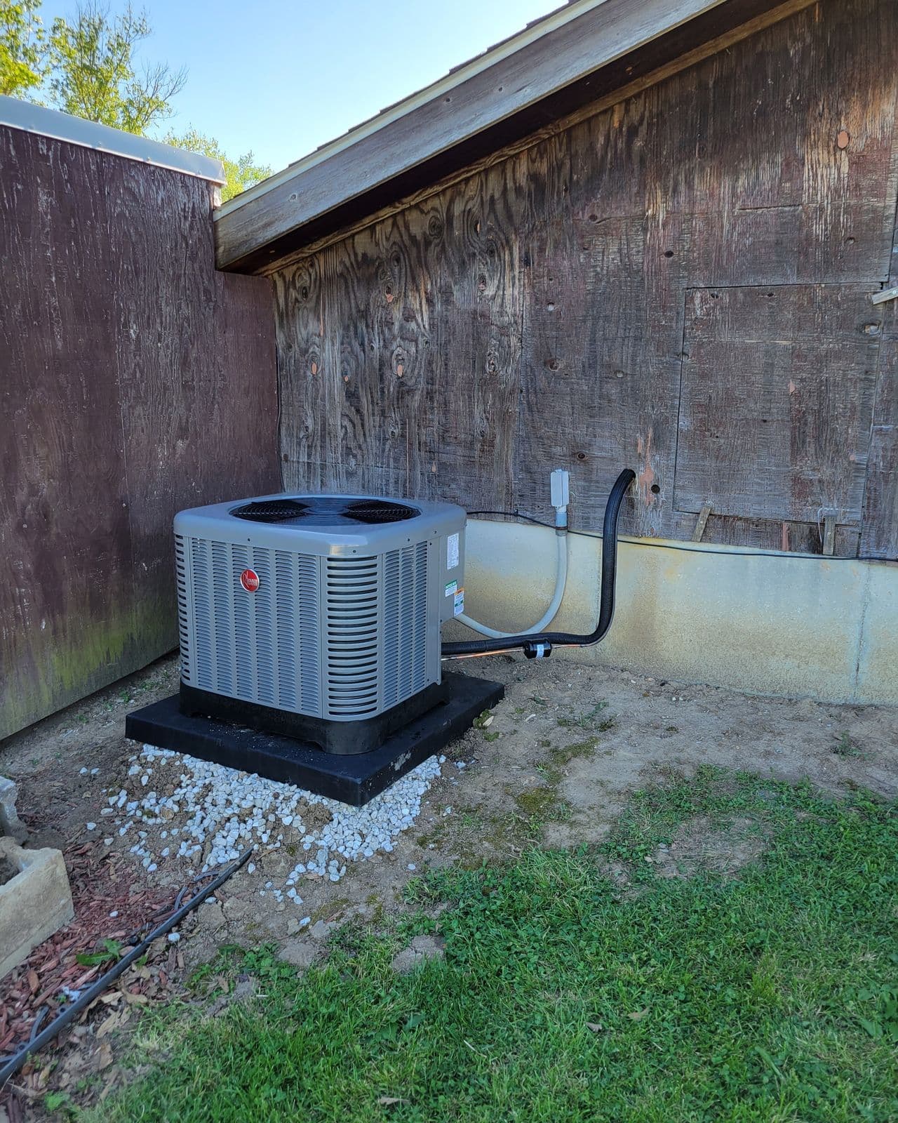 Condenser installed beside a weathered wooden wall