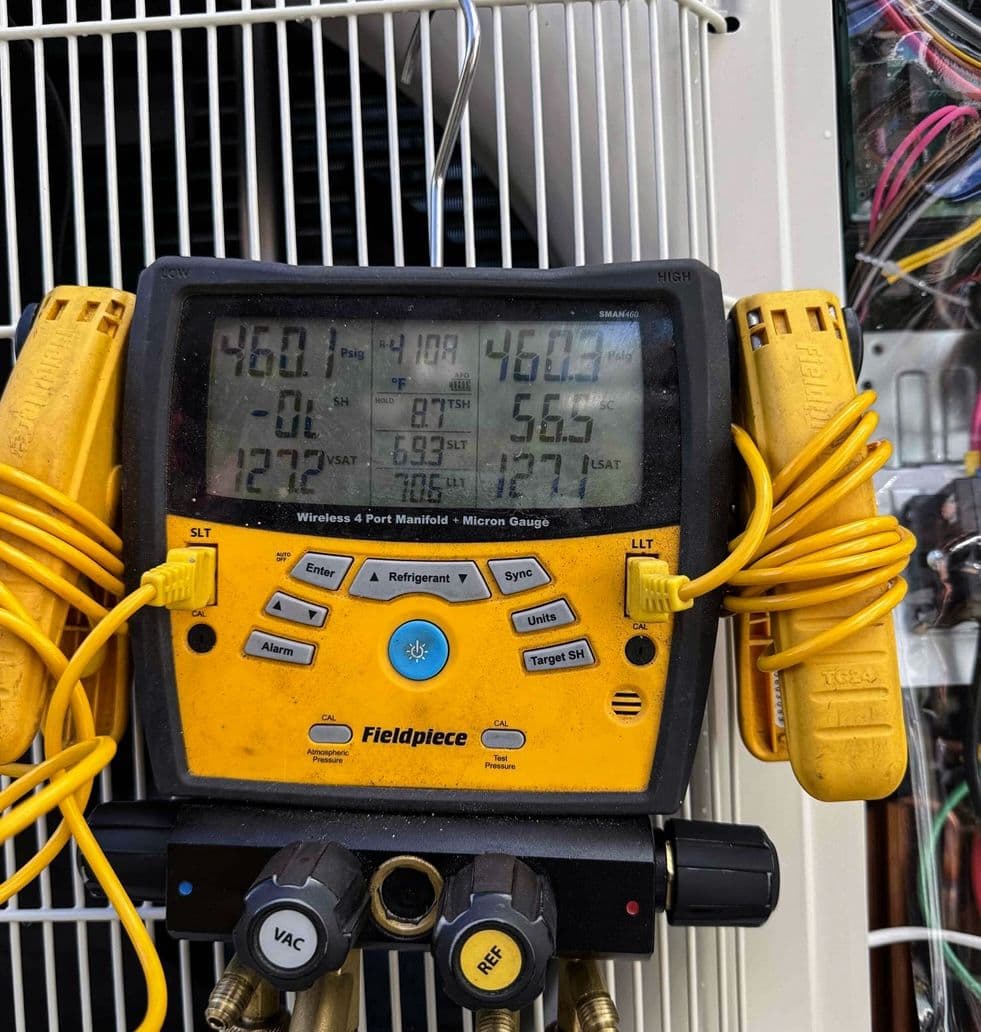 Digital manifold gauge showing refrigerant pressures during an AC checkup