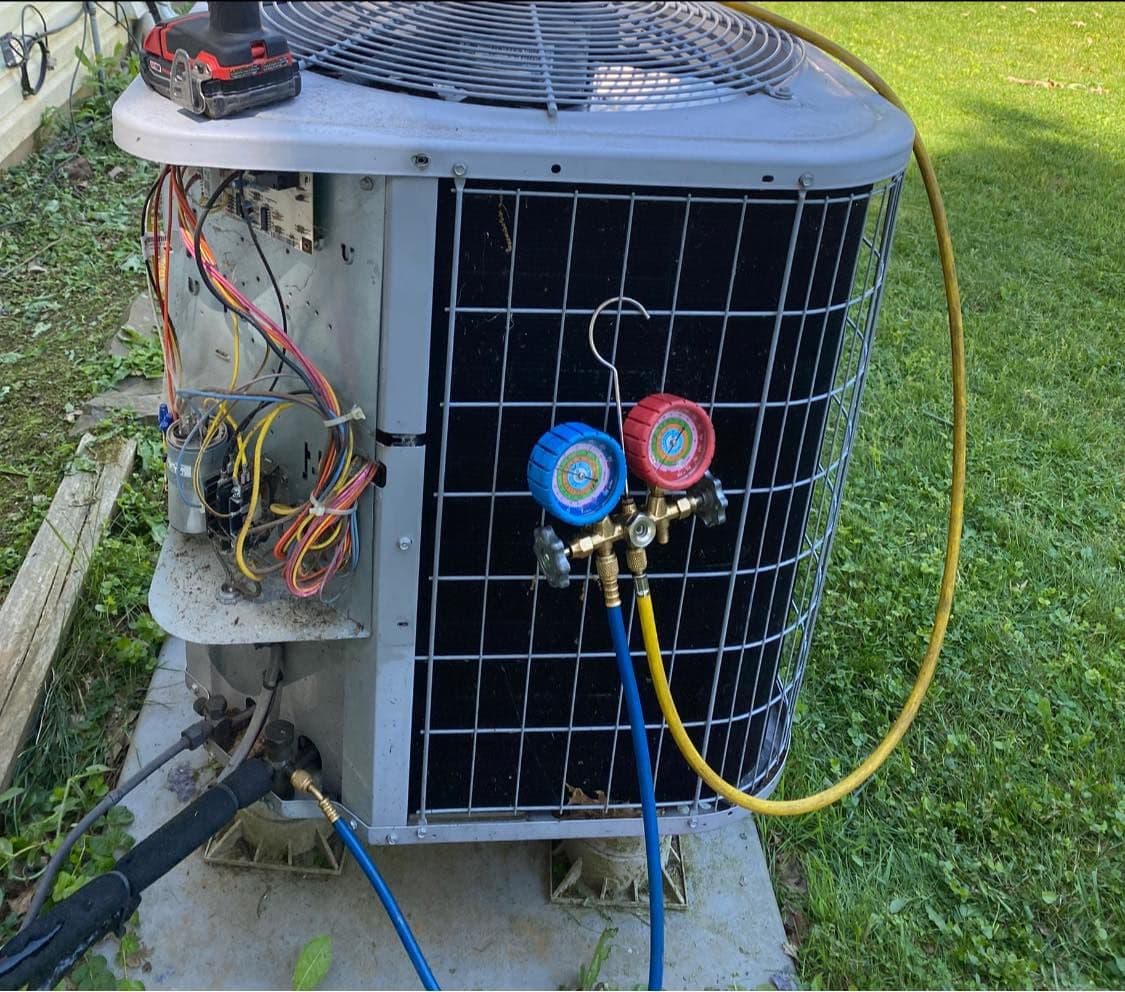 Gauges connected to a condenser during a refrigerant charge check