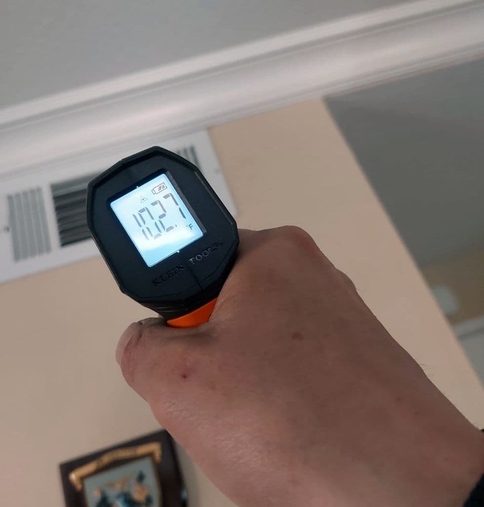Infrared thermometer reading the air temperature at a supply vent