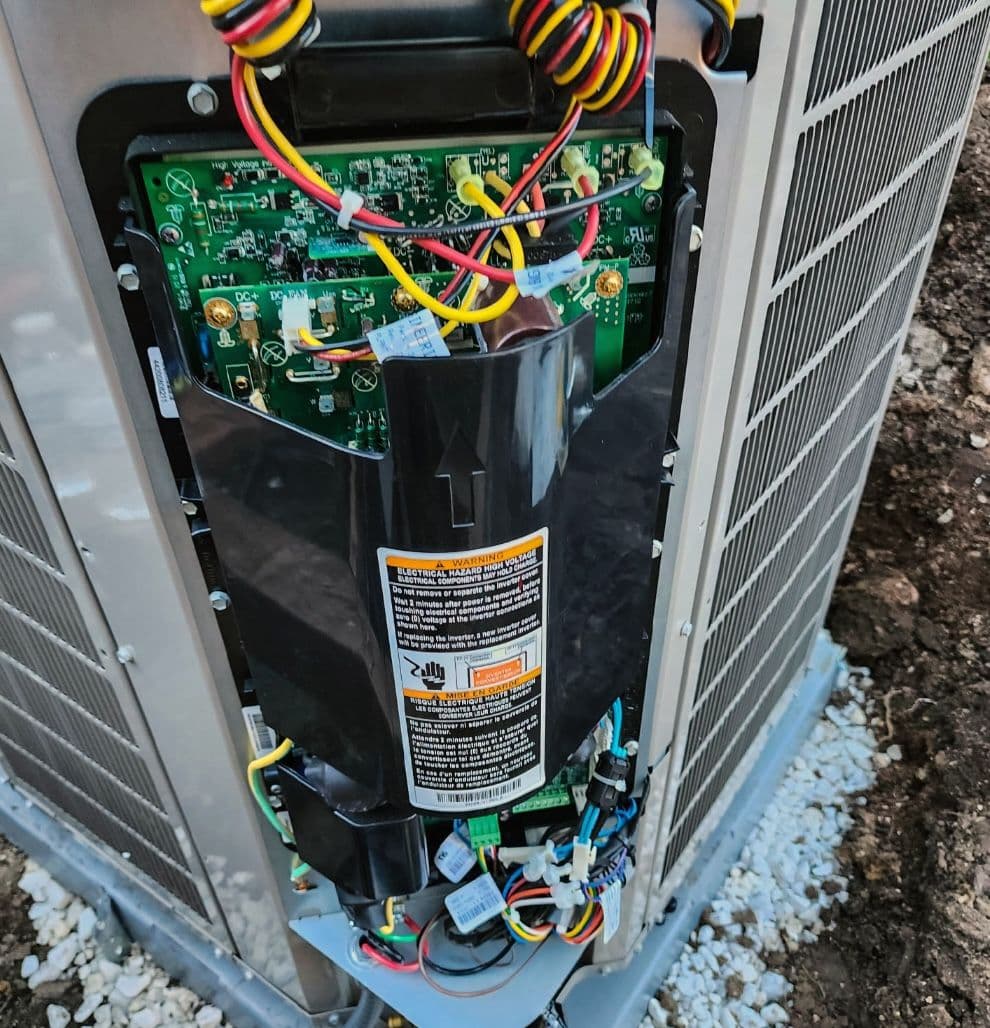 Open outdoor unit showing the control board and compressor