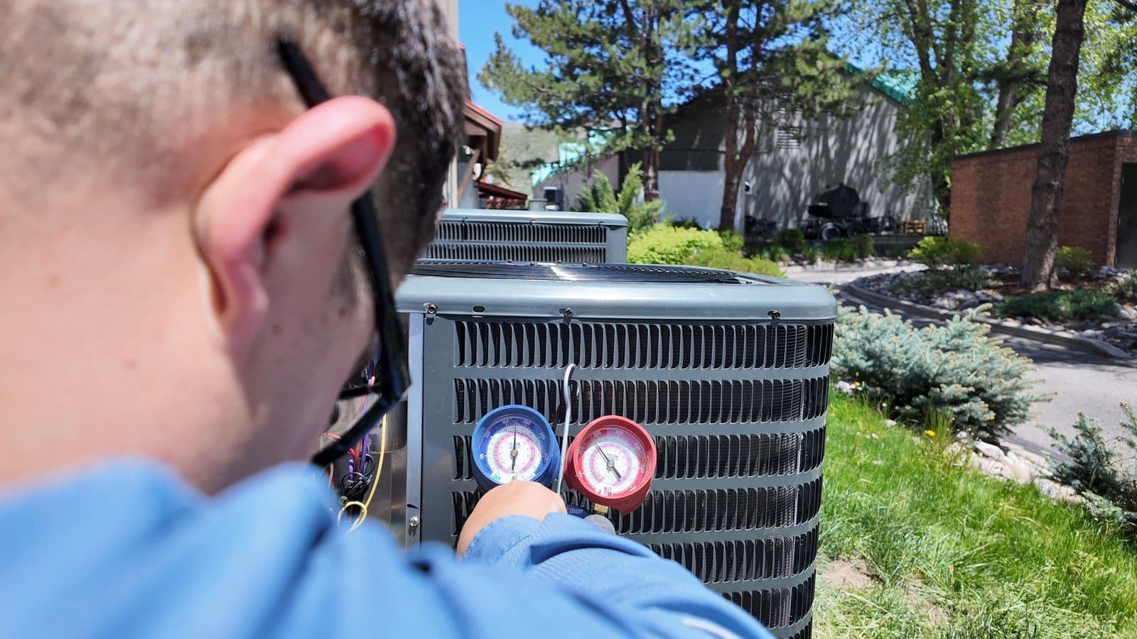 Technician reading refrigerant gauges on a condenser