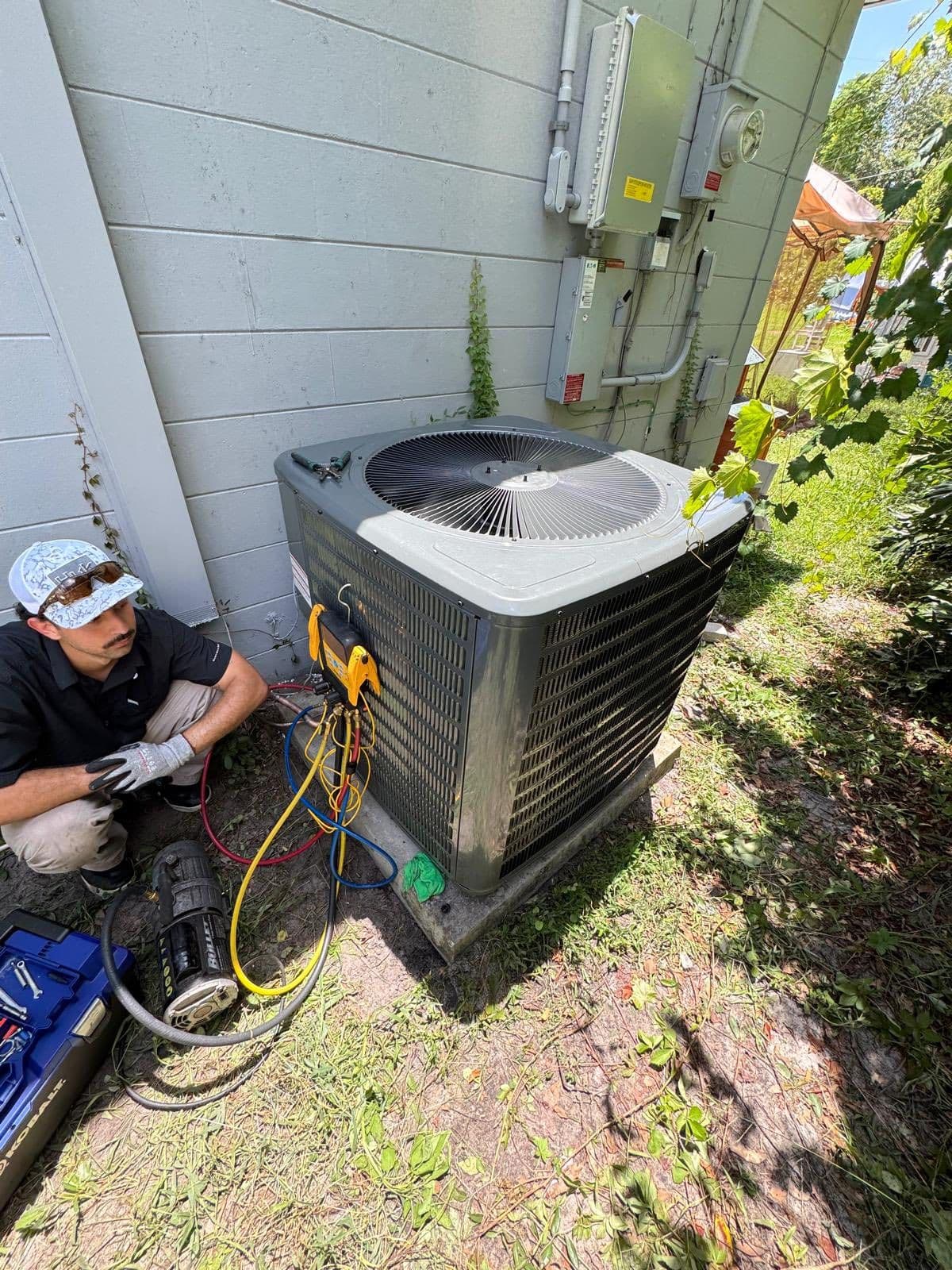 Technician repairing an outdoor air conditioner next to a house