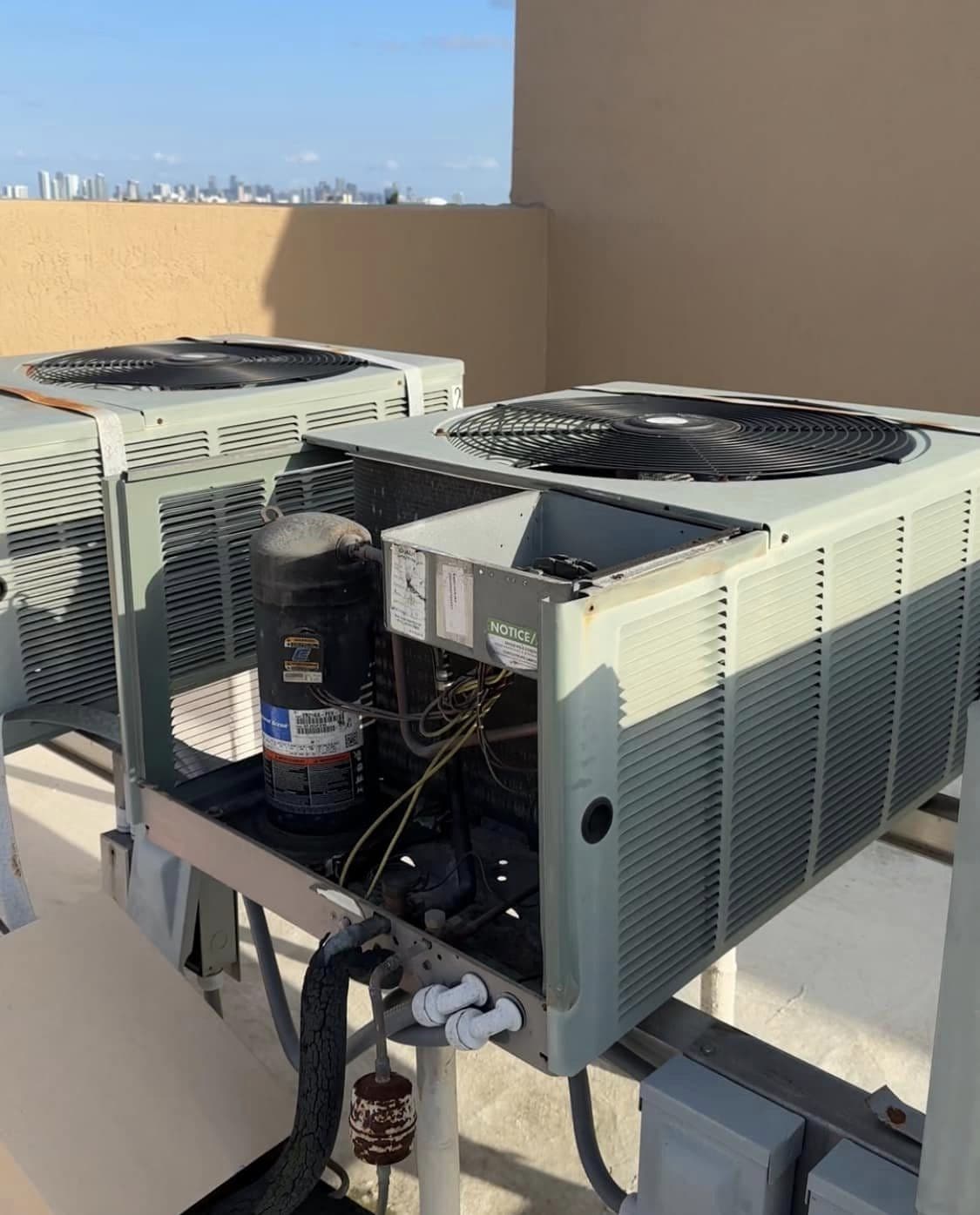 Two rooftop condensing units with covers open during a repair