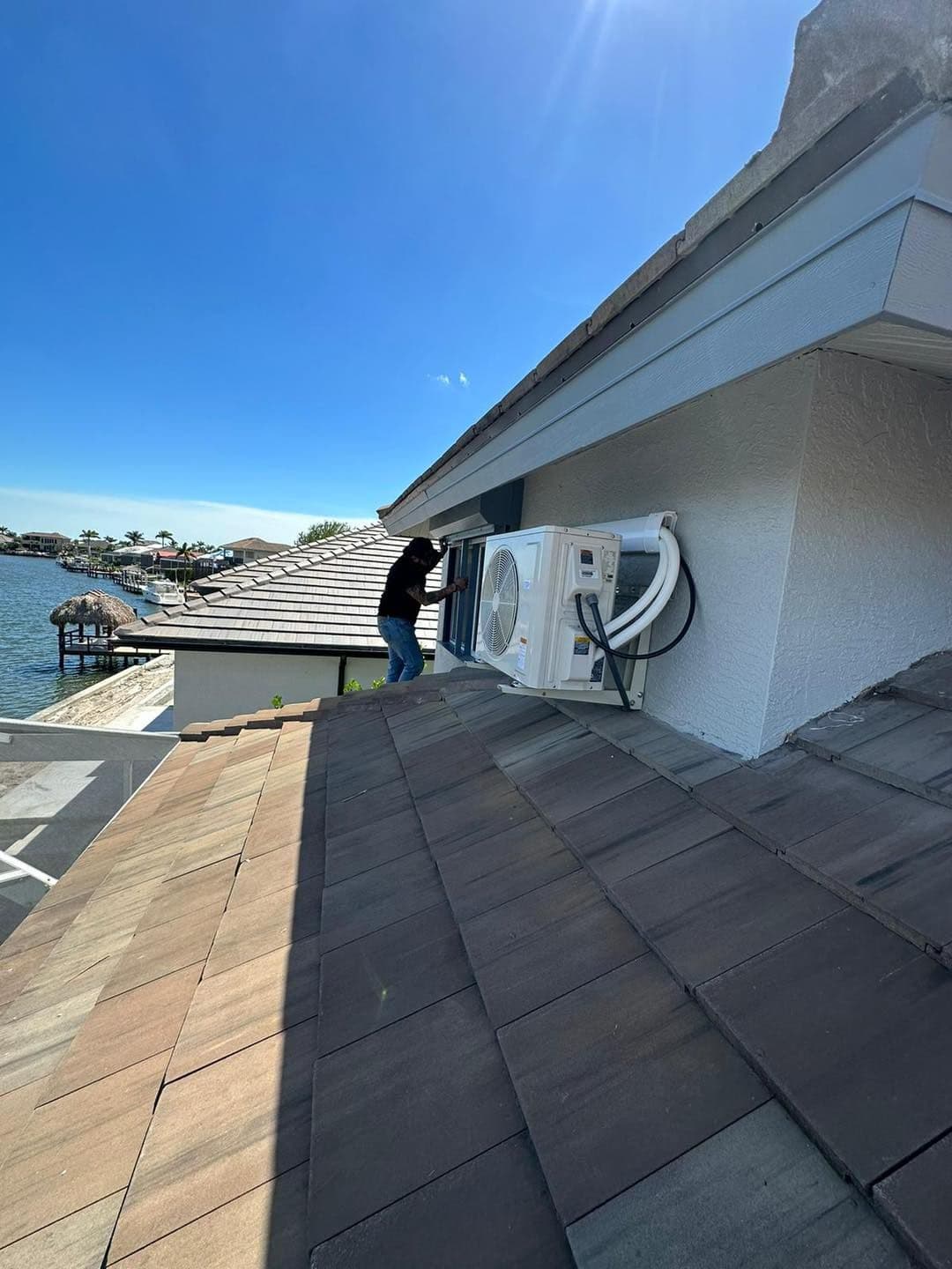 Mini split outdoor unit mounted on a roof beside a waterway