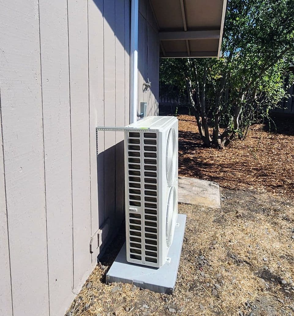 Mini split outdoor unit against a gray wall