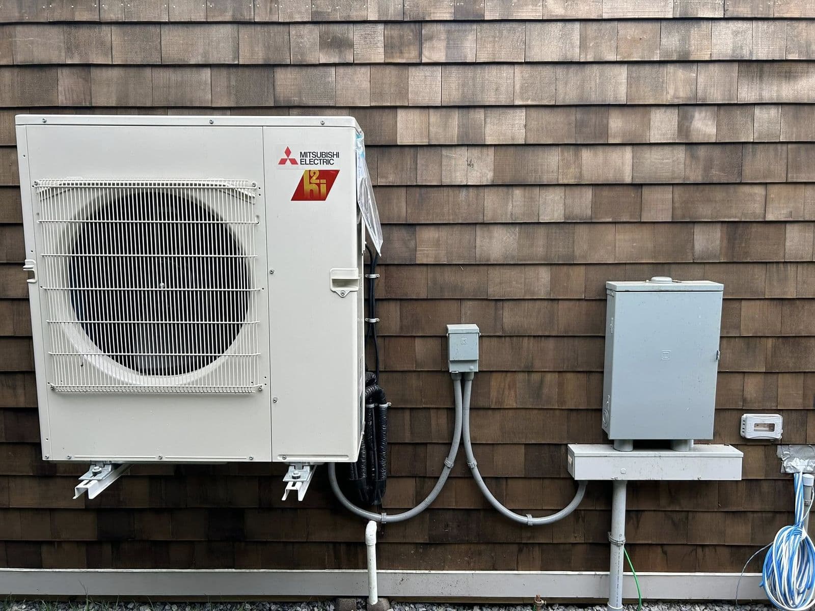 Mini split outdoor unit with an electrical disconnect on wood siding