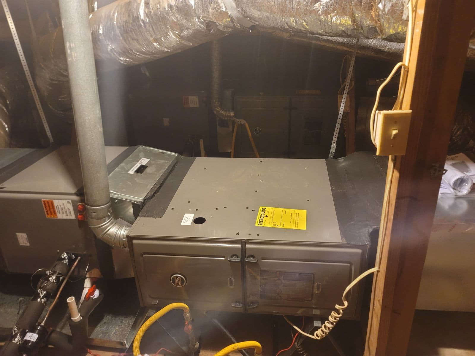Air handler in an attic with a yellow label and gas line