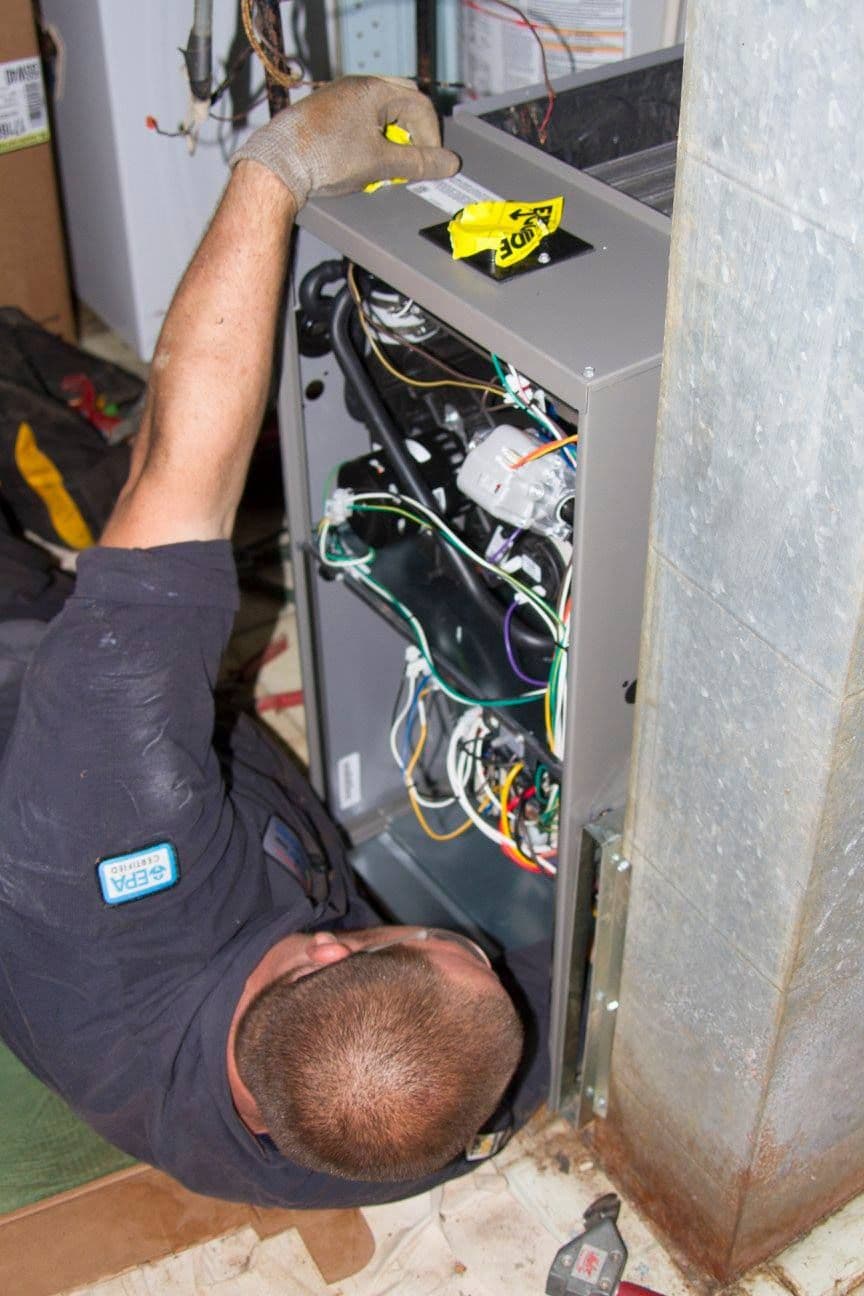 Technician checking gas and wiring connections on a furnace