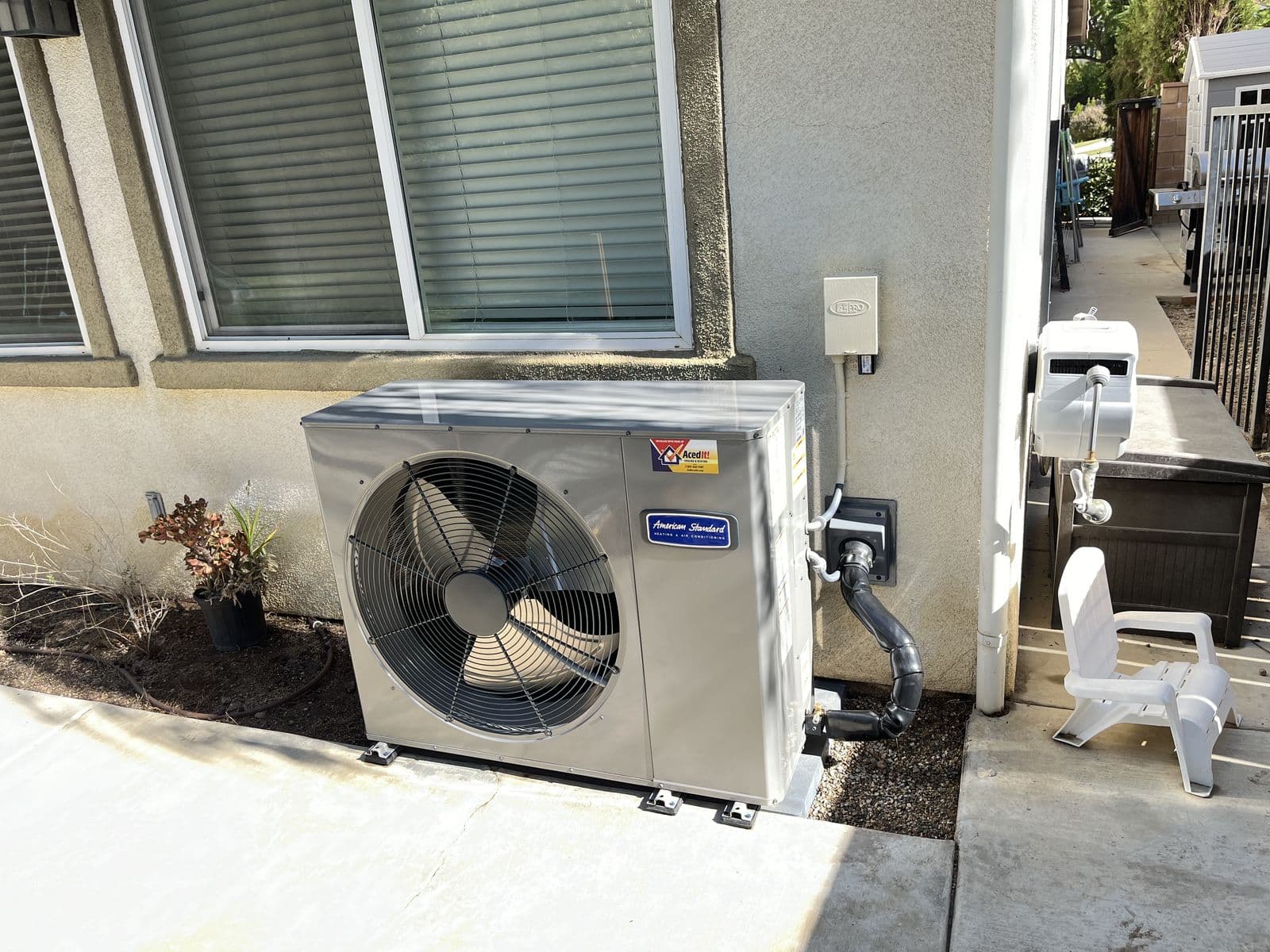 Heat pump outdoor unit beside a stucco house