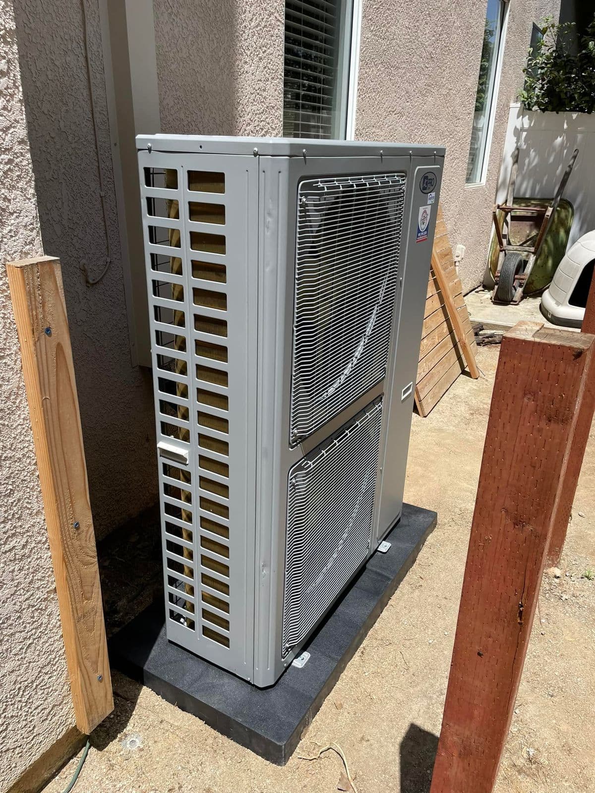 Tall heat pump outdoor unit beside a wooden post