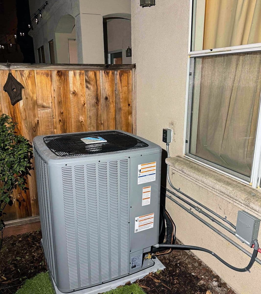 Outdoor air conditioner beside a wood fence