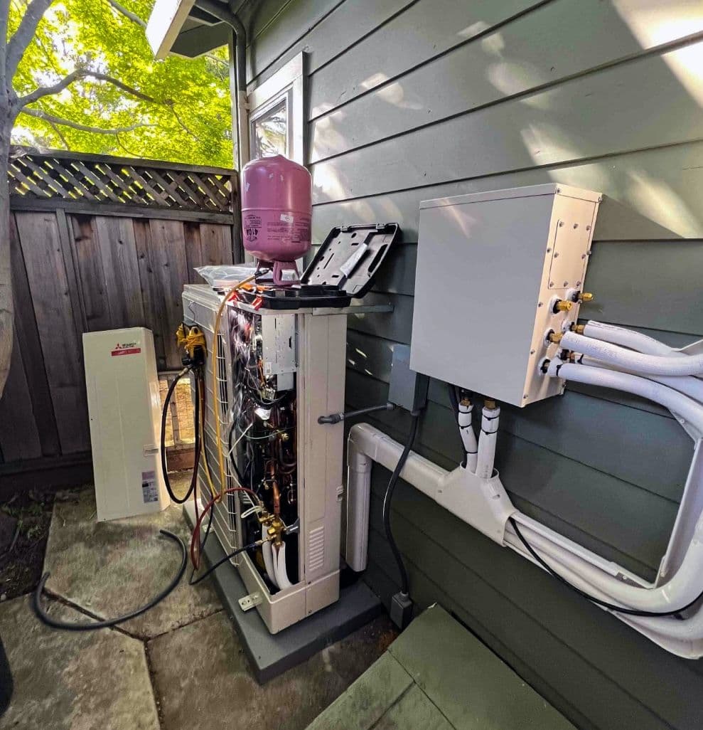 Outdoor unit with equipment connected beside a gray house
