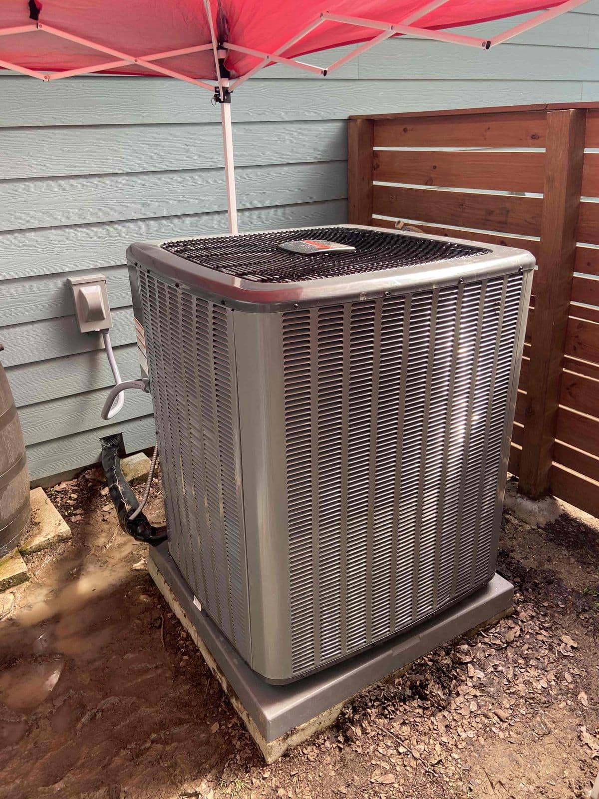 New condenser beside a wood fence