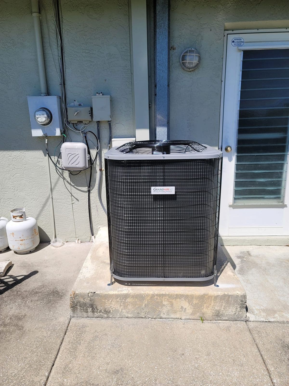 New outdoor air conditioner on a pad beside a house