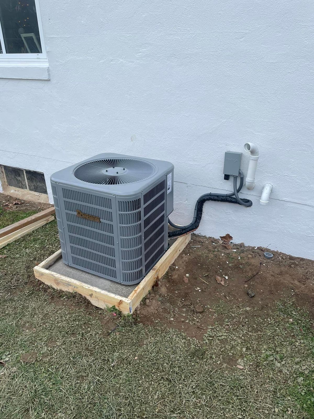 New outdoor unit on a wooden frame near a house