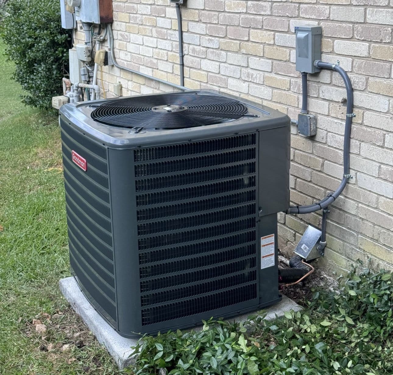 Black condenser beside a brick wall