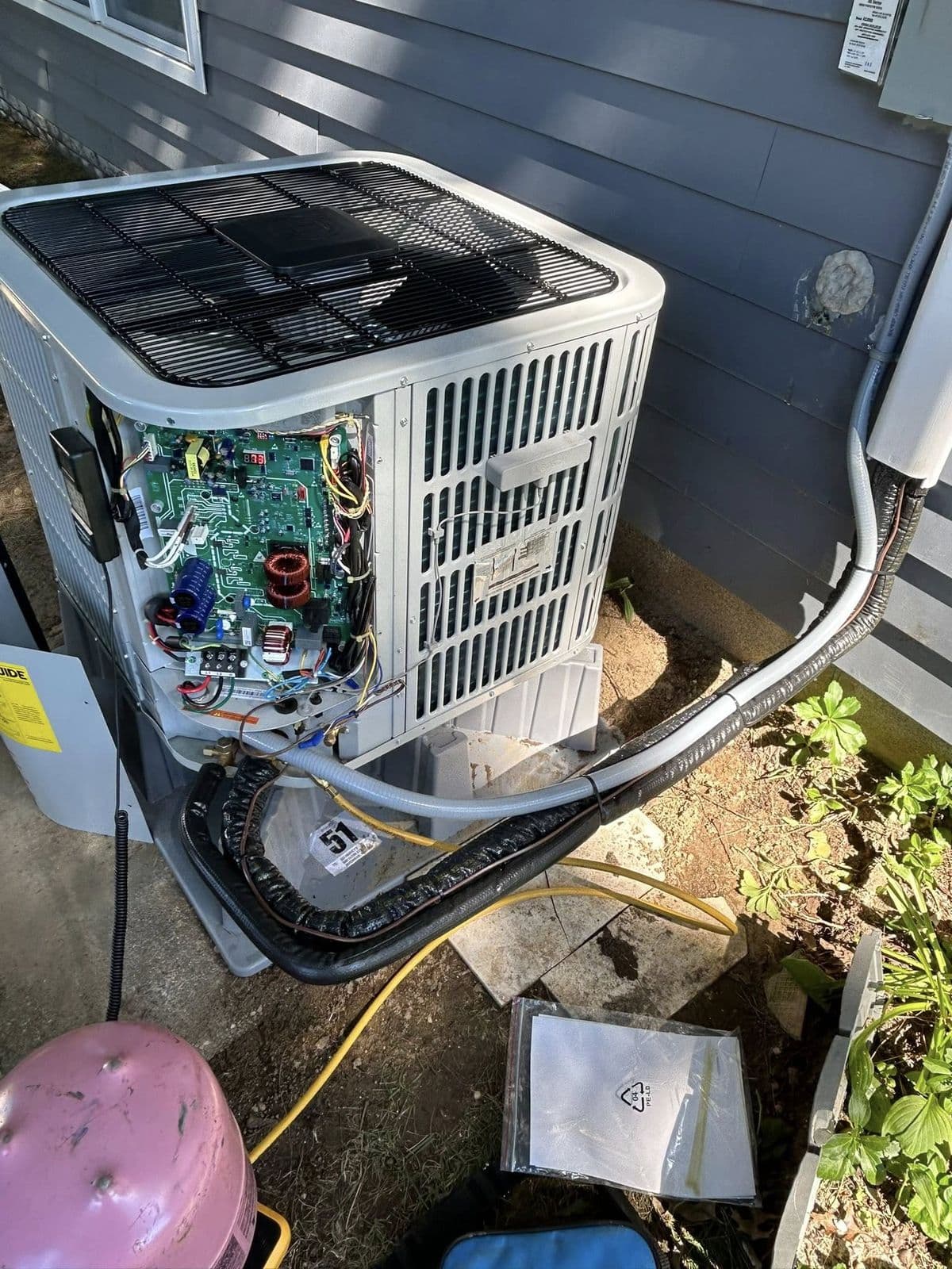 Outdoor unit with the access panel open and a refrigerant tank beside it