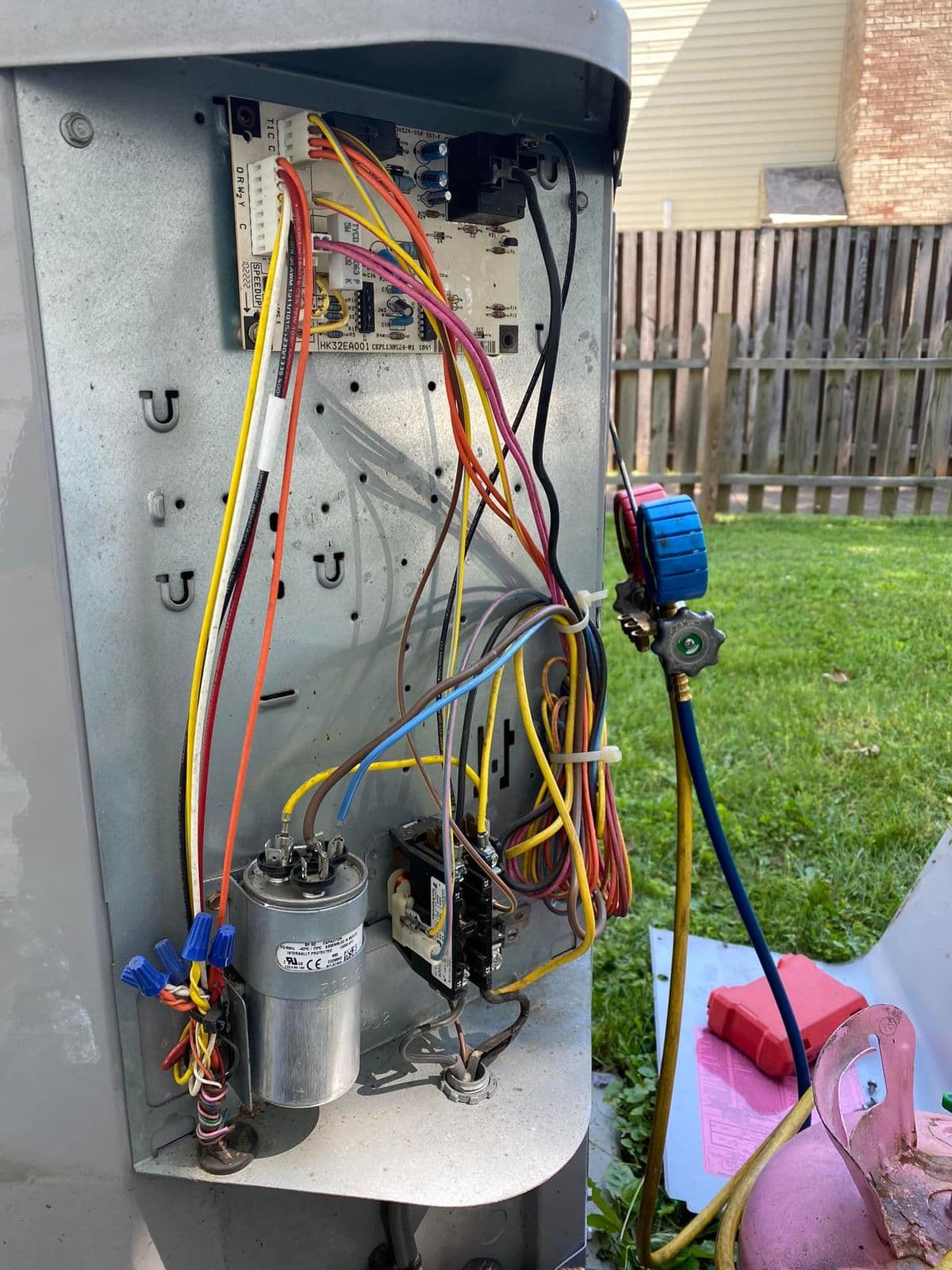 Run capacitor and wiring inside an outdoor air conditioner with gauges attached