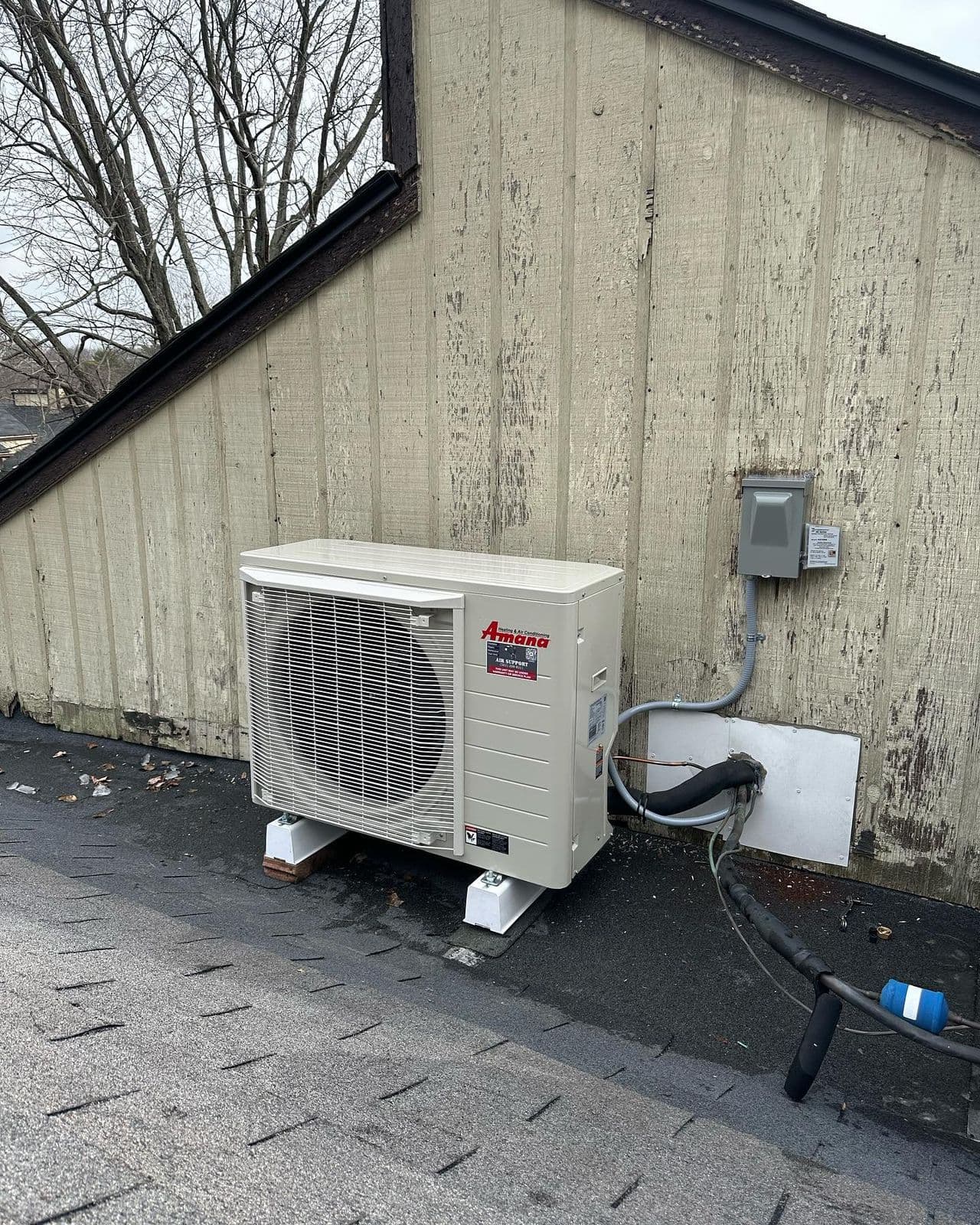 Mitsubishi mini split outdoor unit against wood siding