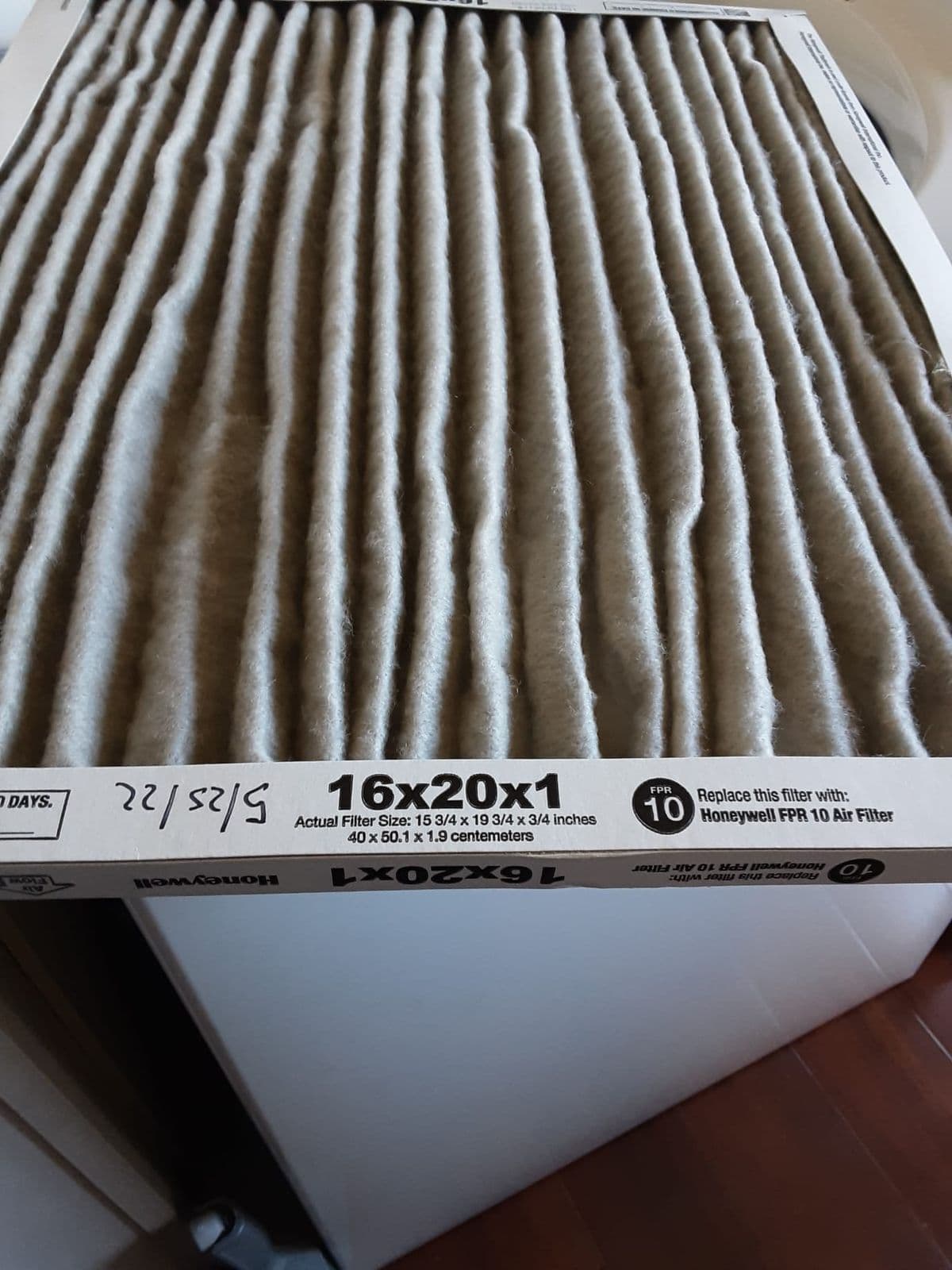 Dirty sixteen by twenty filter held up for inspection