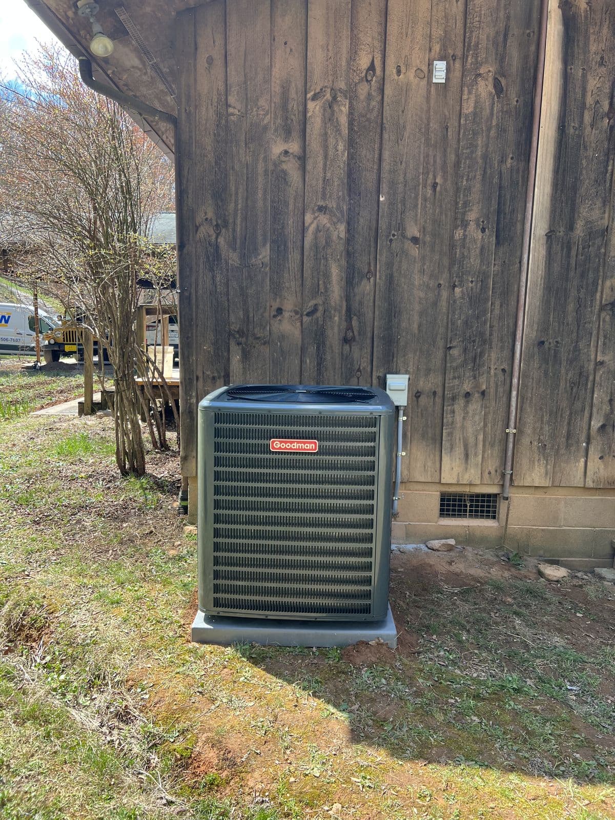 Goodman outdoor unit beside a wood house
