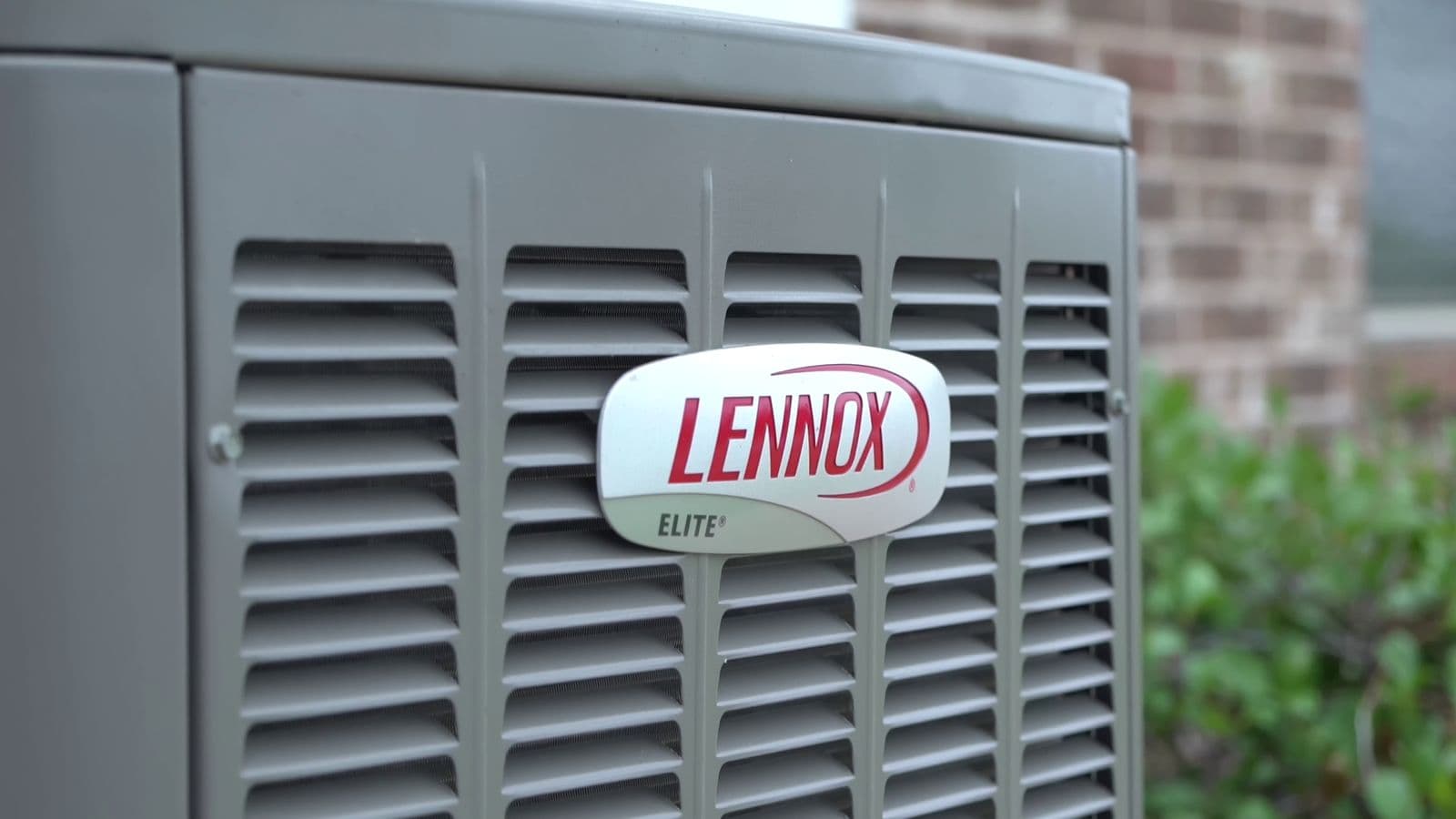 Lennox Elite badge on a condenser beside a brick wall