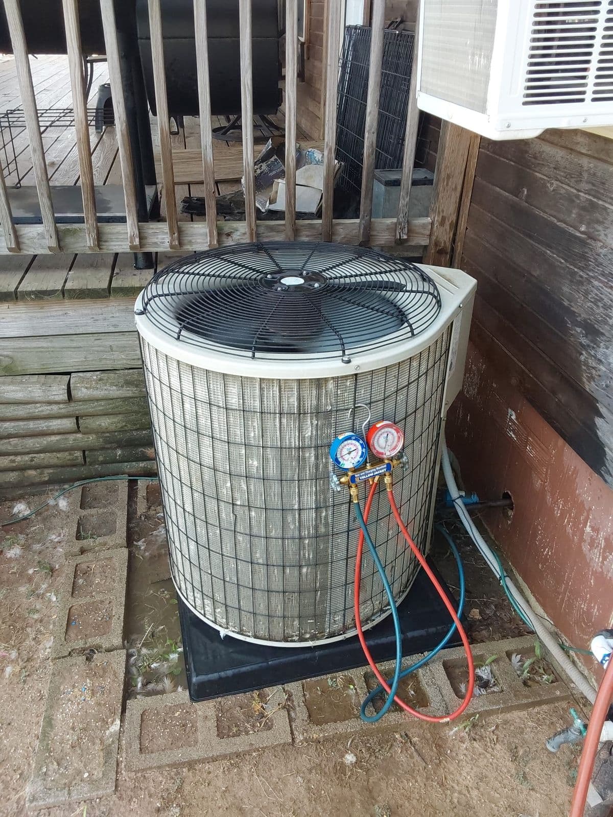 Gauges connected to an older condenser beside a deck