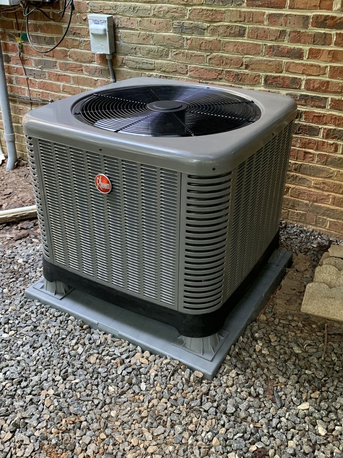 New Rheem condenser beside a brick wall