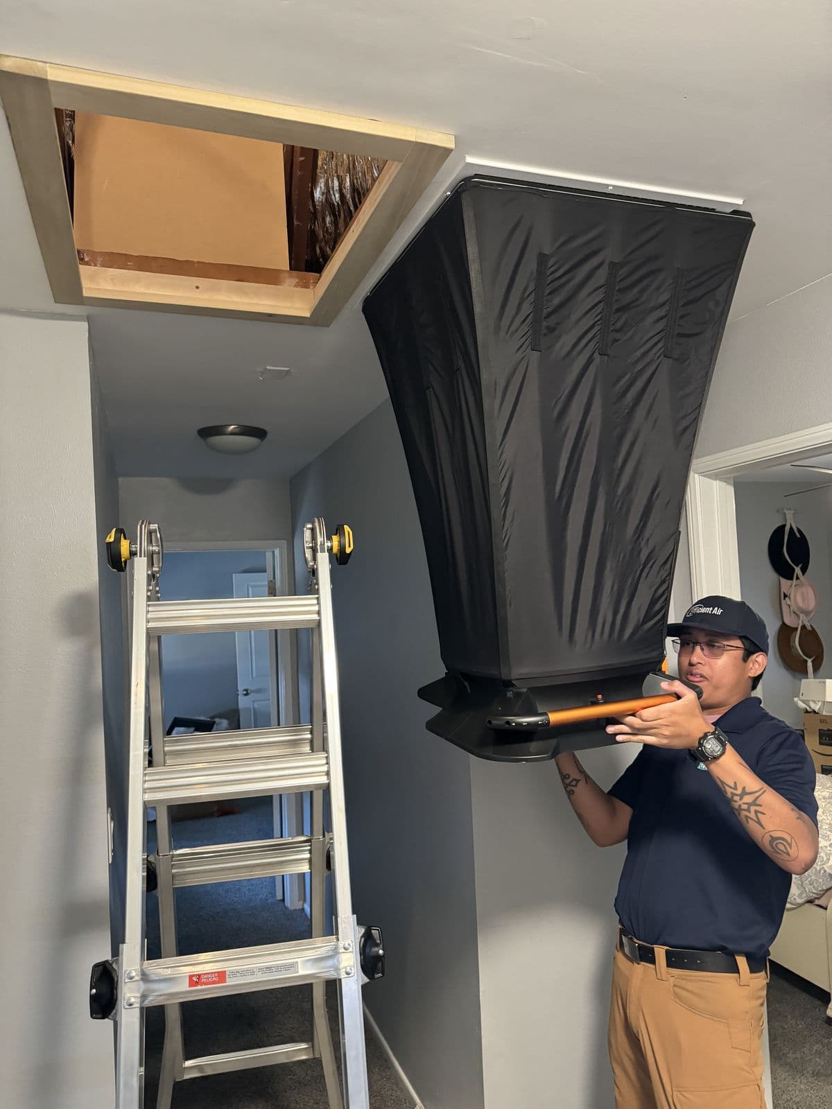 Technician fitting a duct plenum at an attic hatch