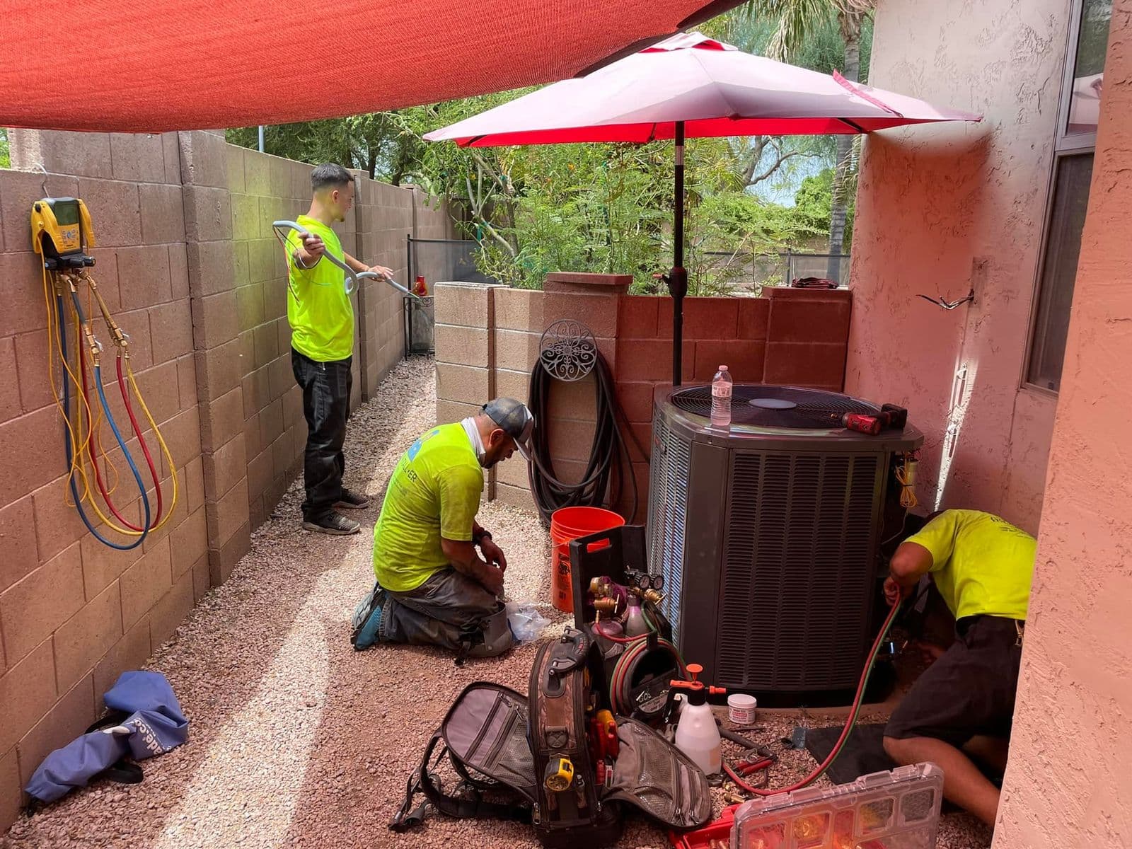 Technicians in high visibility vests installing an air conditioner in a side yard