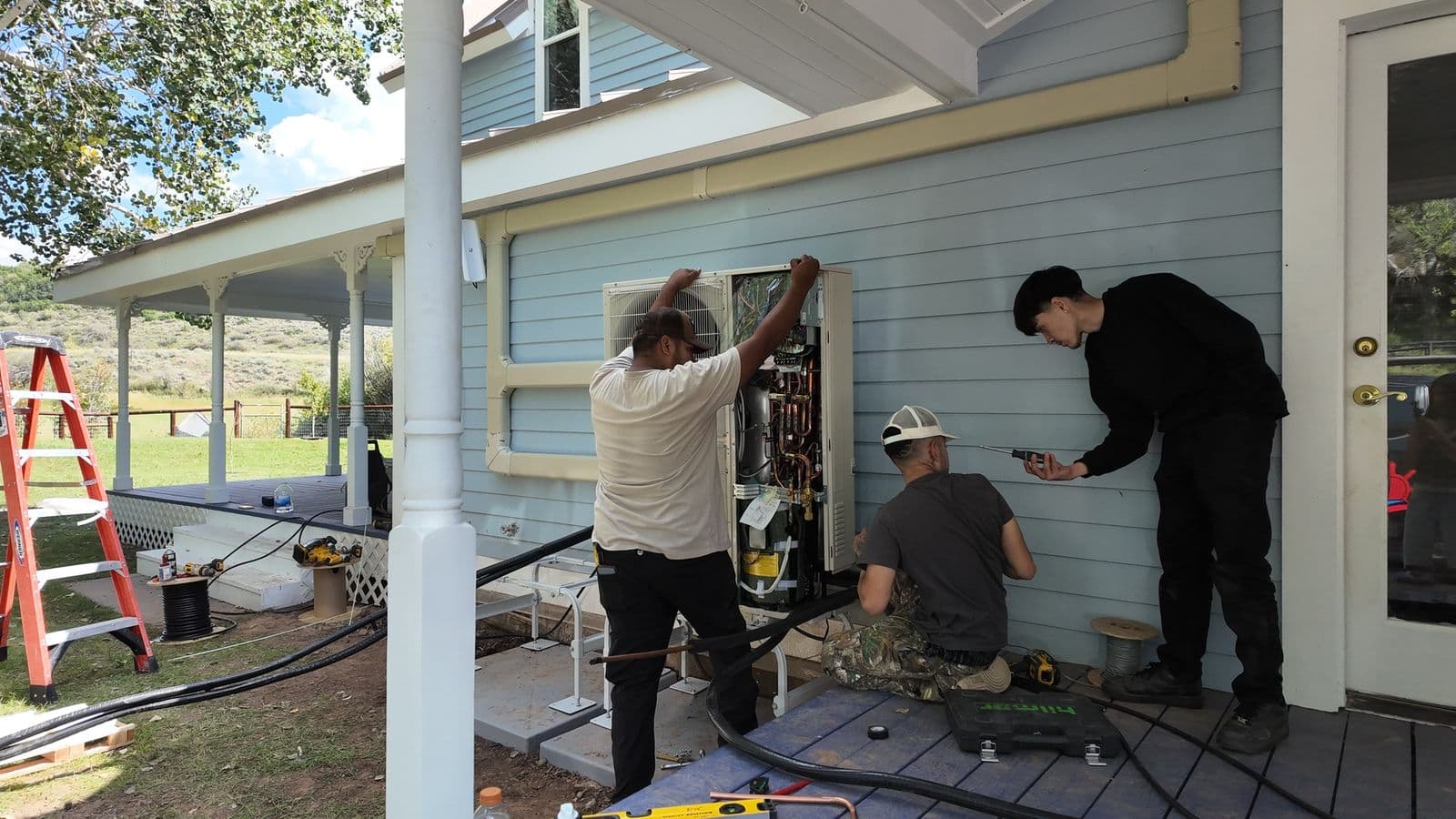 Three technicians working at the back of a house