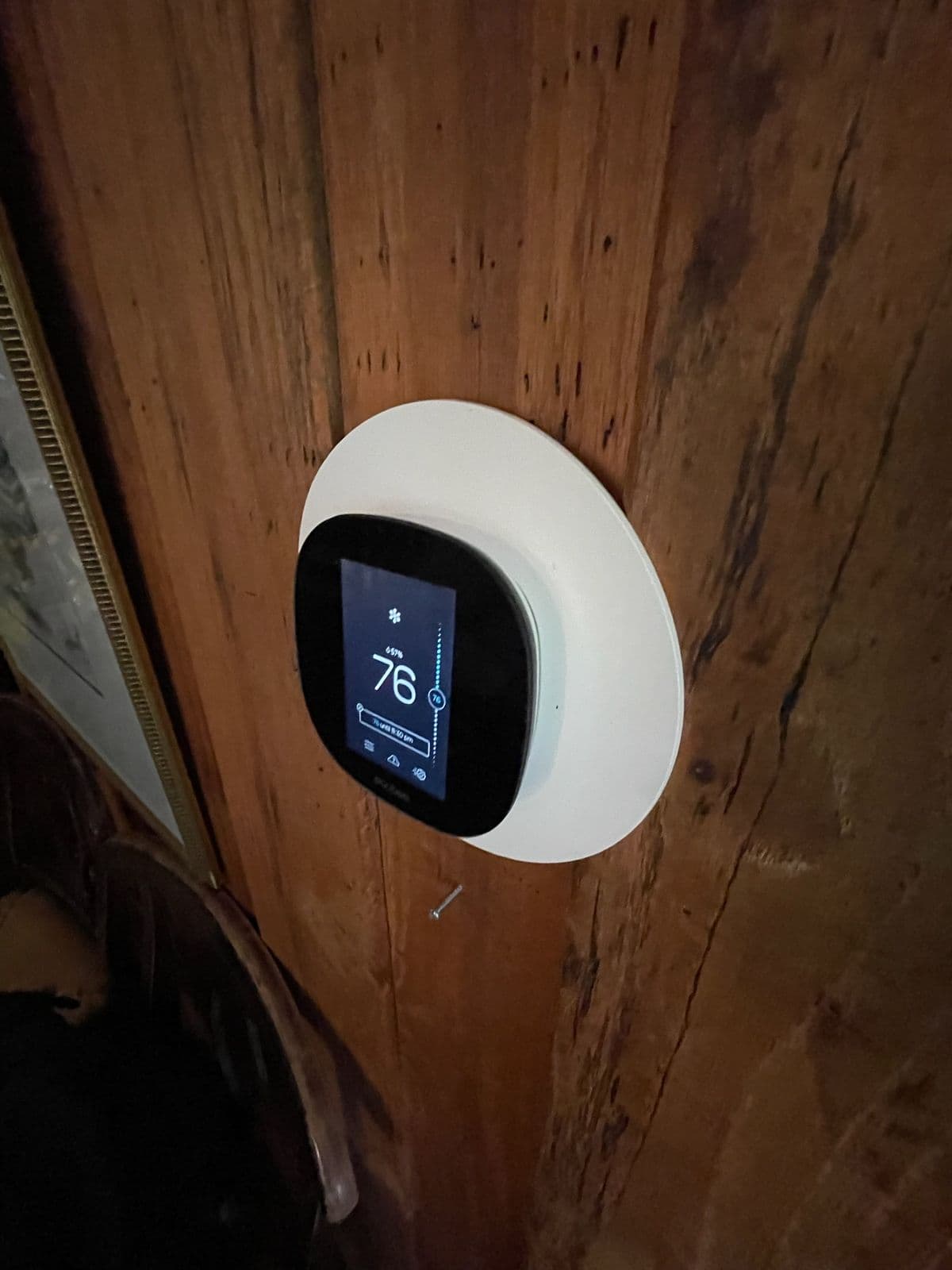 Round smart thermostat on a wood wall